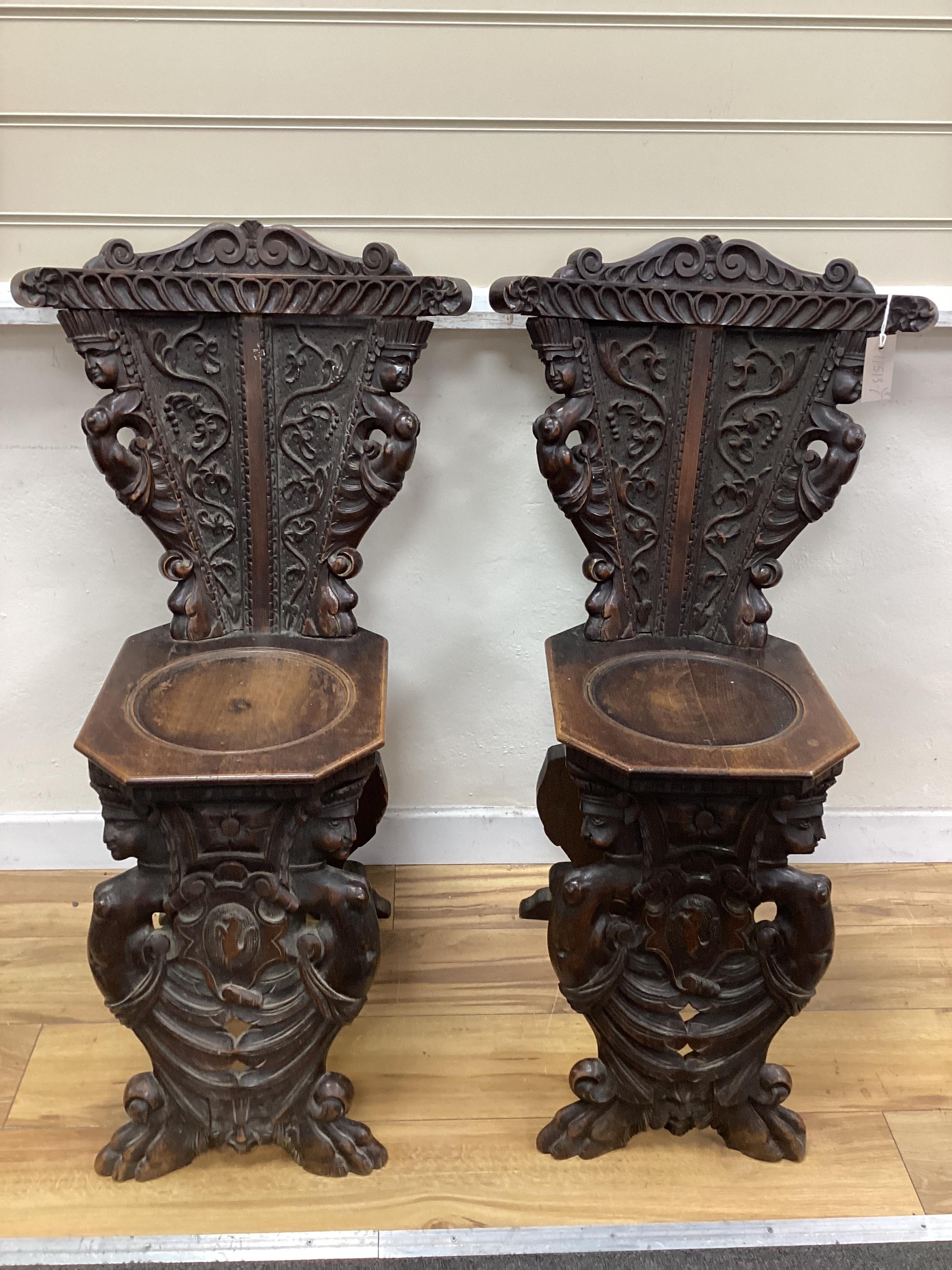 A pair of 18th century style Italian carved walnut hall chairs, width 48cm, depth 42cm, height 94cm.